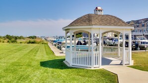A gazebo with a peaked roof and a small tower, surrounded by a row of boats.