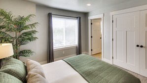 A bedroom with a bed, a plant, a window with blinds, and a door. - Garden City Townhome, Close to Parks + Downtown! (Garden City)
