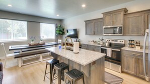 A modern kitchen with a central island, stainless steel appliances, and a large window providing natural light. - Garden City Townhome, Close to Parks + Downtown! (Garden City)