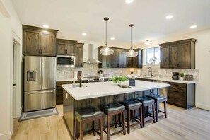 A modern kitchen with stainless steel appliances, dark wood cabinets, and a central island with bar stools. - Garden City Vacation Rental: Walk to Bear Lake (Garden City)