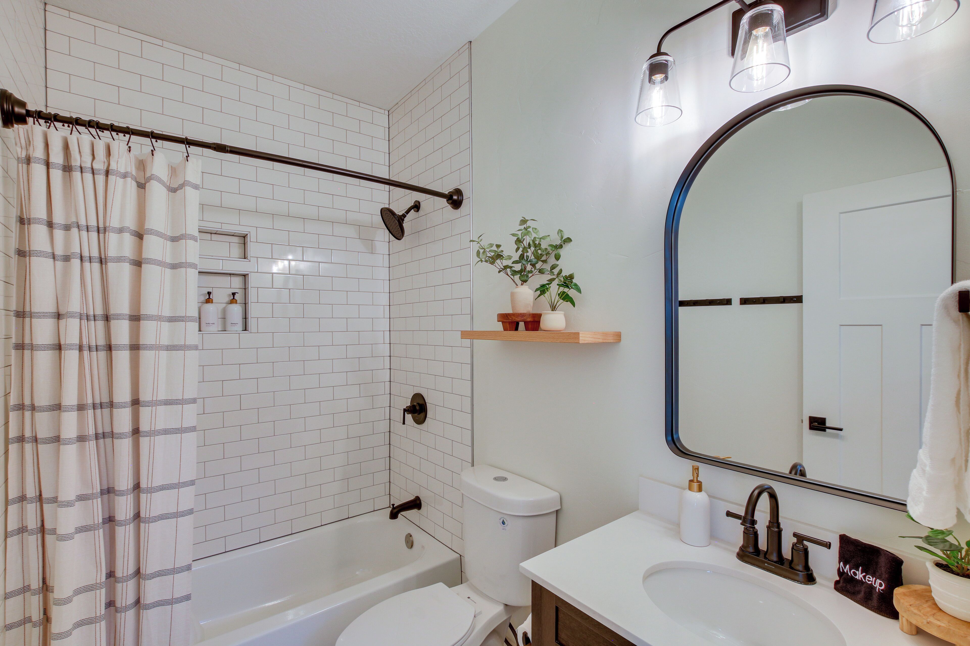 A bathroom with a bathtub, toilet, sink, and a mirror.