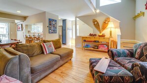 A spacious living room with a brown sofa, patterned ottoman, and a wooden coffee table. A dining area with a table and chairs is visible in the background. - Incline Village Retreat Near Skiing & Beaches (Incline Village)