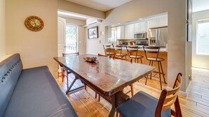 A dining area with a wooden table and benches, a kitchen with white cabinets and appliances, and a wall-mounted clock. - Incline Village Retreat Near Skiing & Beaches (Incline Village)