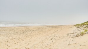A sandy beach with gentle waves and sparse vegetation. - Nags Head Vacation Rental w/ Hot Tub: Near Beach! (Nags Head)