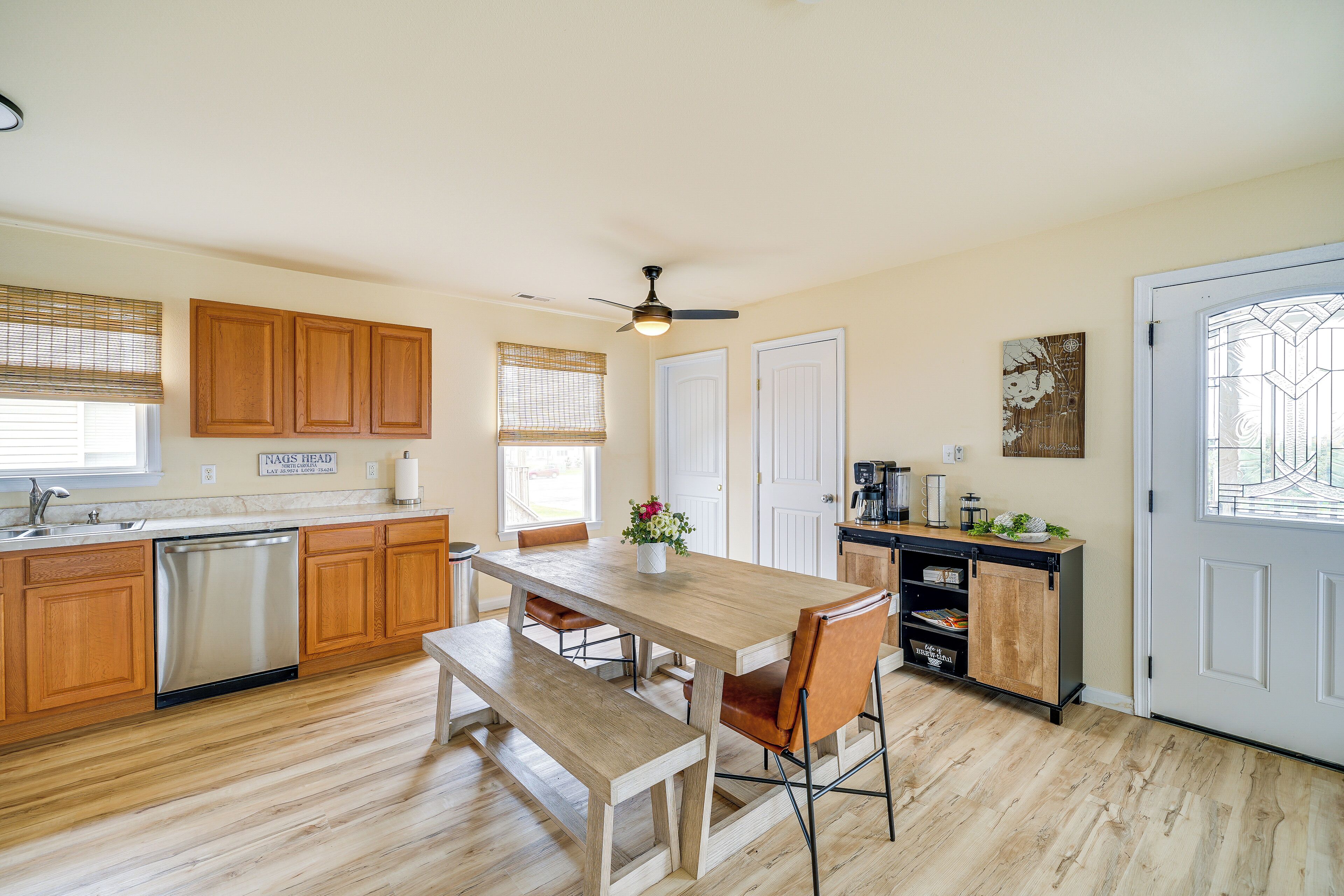 A kitchen with wooden cabinets, a dining table, and a bench.