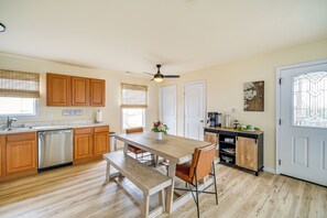 A kitchen with wooden cabinets, a dishwasher, a dining table with chairs, and a bench. - Nags Head Vacation Rental w/ Hot Tub: Near Beach! (Nags Head)