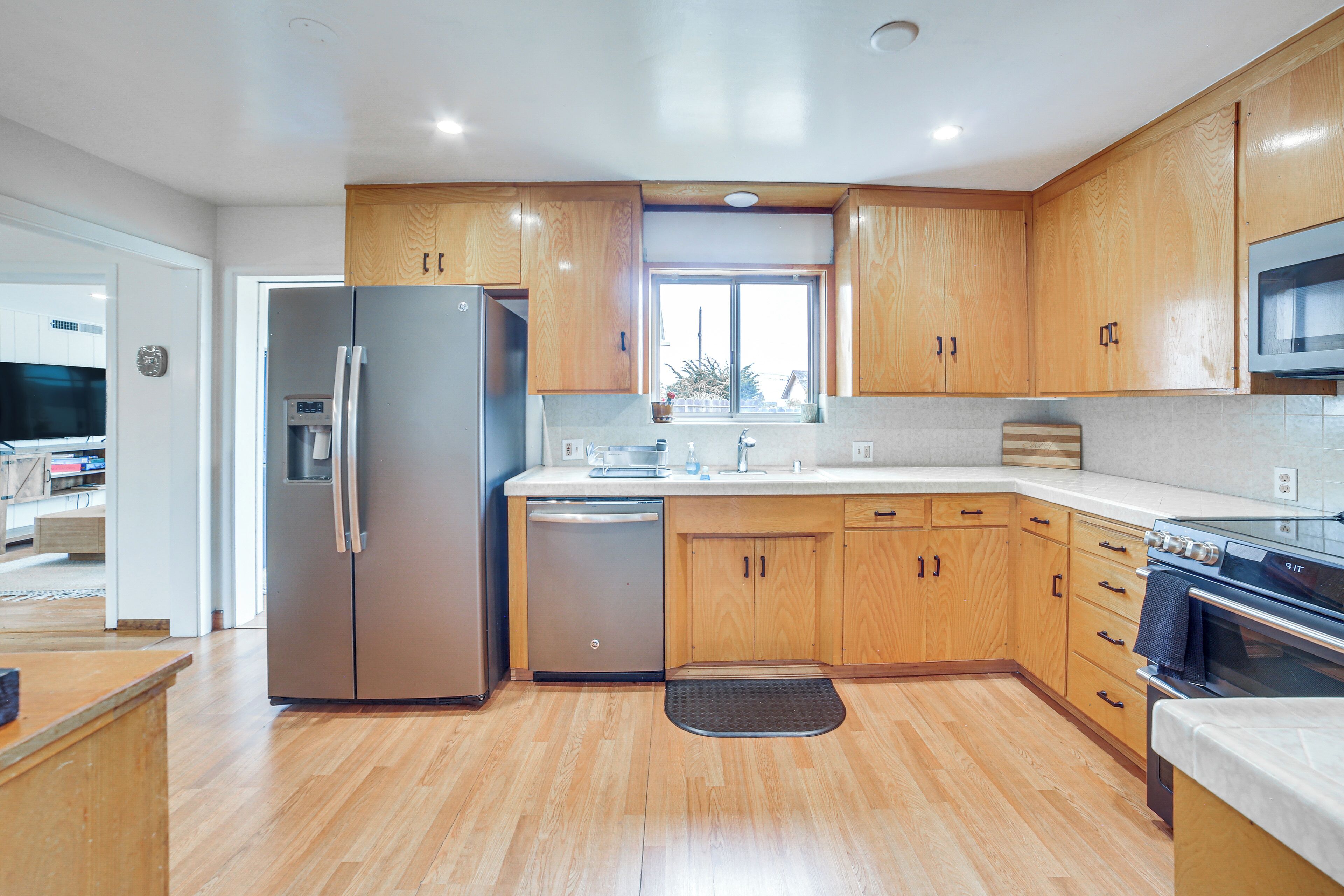 A modern kitchen with wooden cabinets, stainless steel appliances, and a large window.