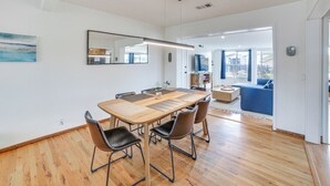 A modern dining area with a wooden table, leather chairs, and a large mirror. - Seaside Vacation Rental w/ Patio Near Monterey Bay (Seaside)