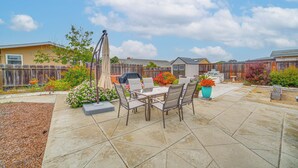 A patio with a table and chairs, surrounded by a wooden fence and various plants. - Seaside Vacation Rental w/ Patio Near Monterey Bay (Seaside)