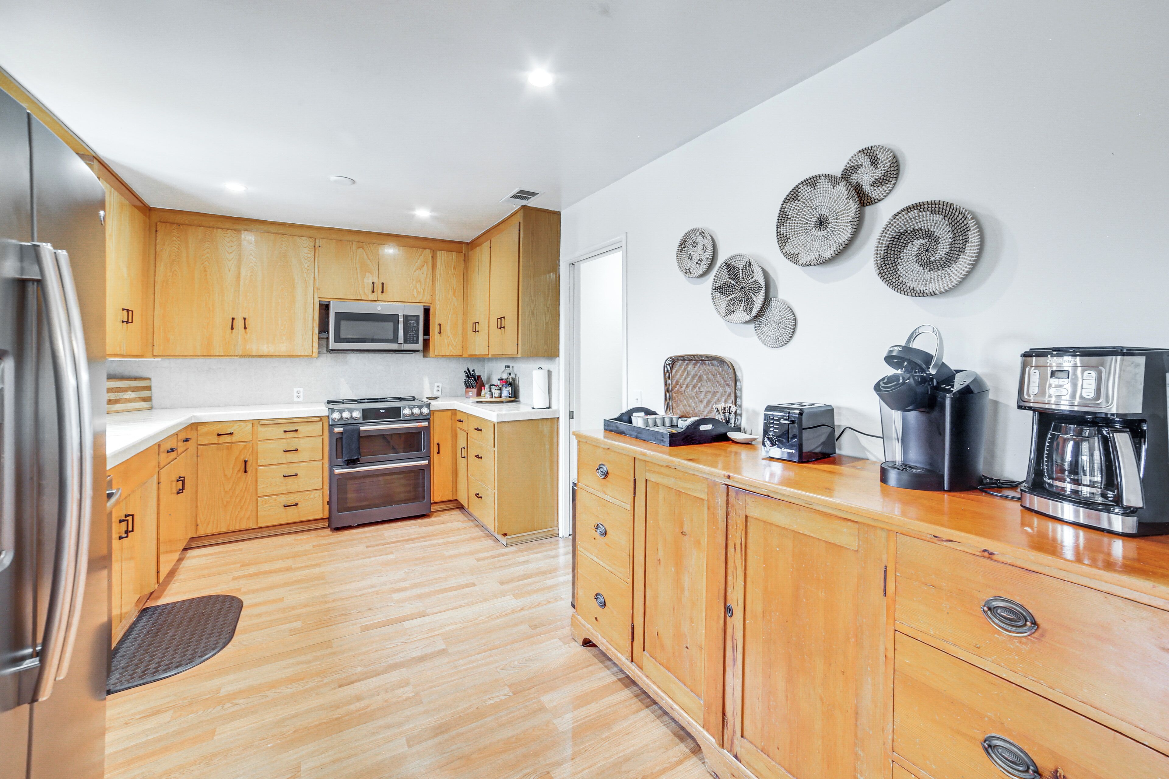 Una cocina moderna con armarios de madera, electrodomésticos de acero inoxidable y platos decorativos en la pared.