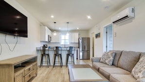 A modern kitchen with white cabinets, a stainless steel refrigerator, and a flat-screen TV mounted on the wall. - Community Pool Access: Rehoboth Beach Unit! (Rehoboth Beach)