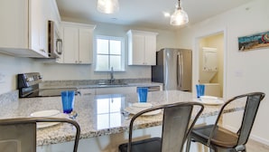 A kitchen with white cabinets, a granite countertop, stainless steel appliances, and bar stools. - Community Pool Access: Rehoboth Beach Unit! (Rehoboth Beach)