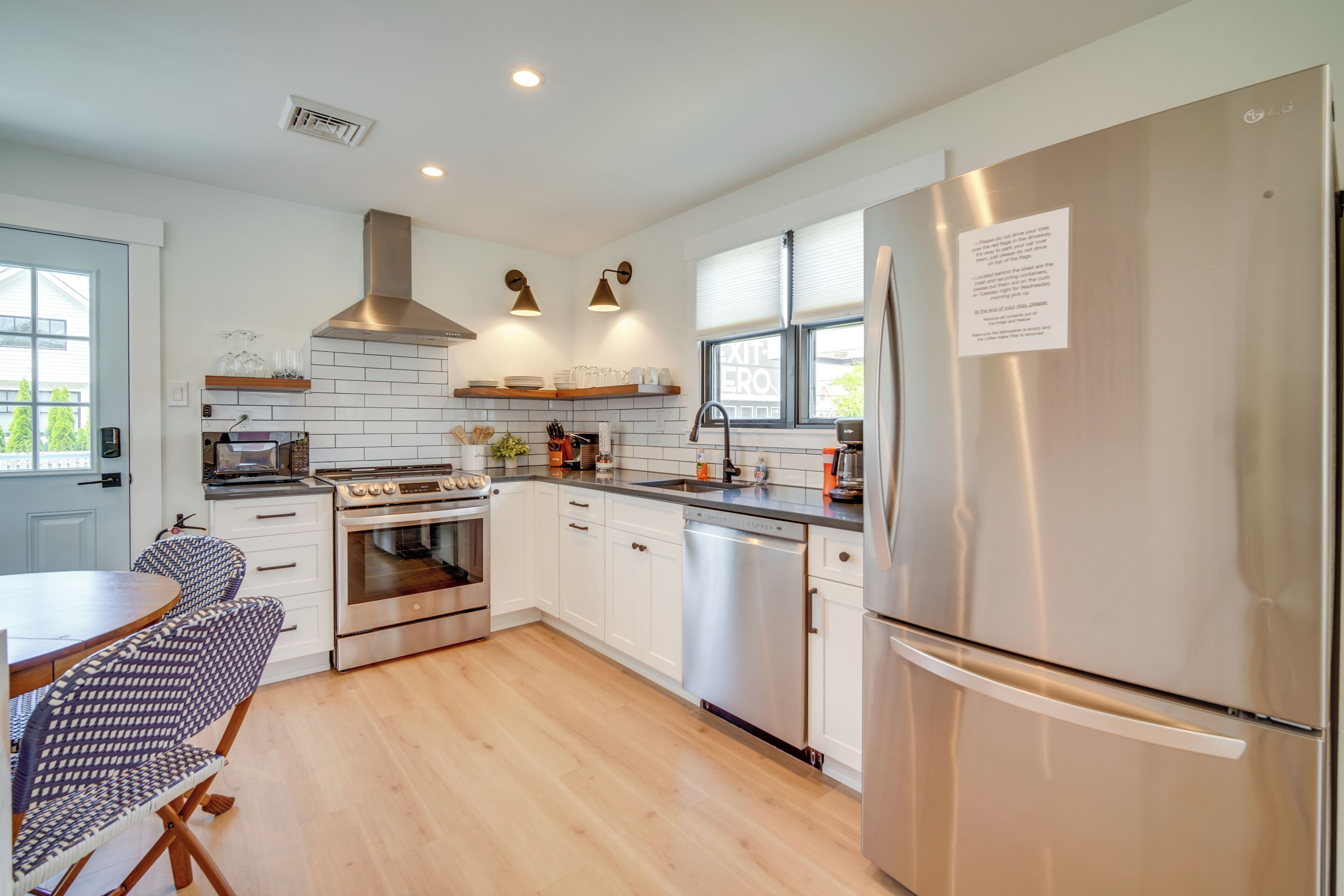 A modern kitchen with white cabinets, stainless steel appliances, and a dining area with patterned chairs.