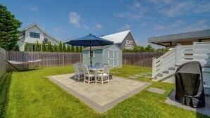 A backyard with a patio, a swing, and a covered grill area. - Beautiful Cape May Cottage: Walk to Beach & Mall! (Cape May)