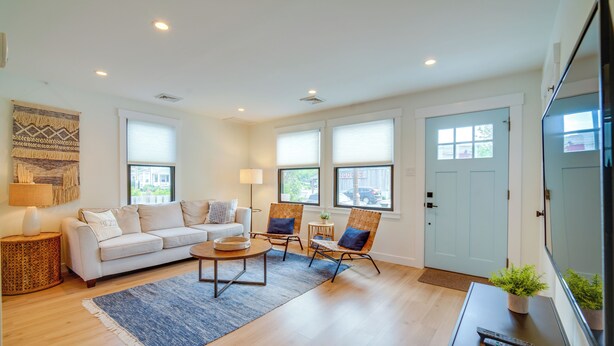 A living room with a sofa, two armchairs, a coffee table, and a TV. - Beautiful Cape May Cottage: Walk to Beach & Mall! (Cape May)