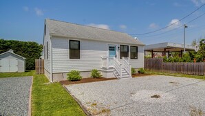 A single-story house with a front porch, a small front yard, and a gravel driveway. - Beautiful Cape May Cottage: Walk to Beach & Mall! (Cape May)