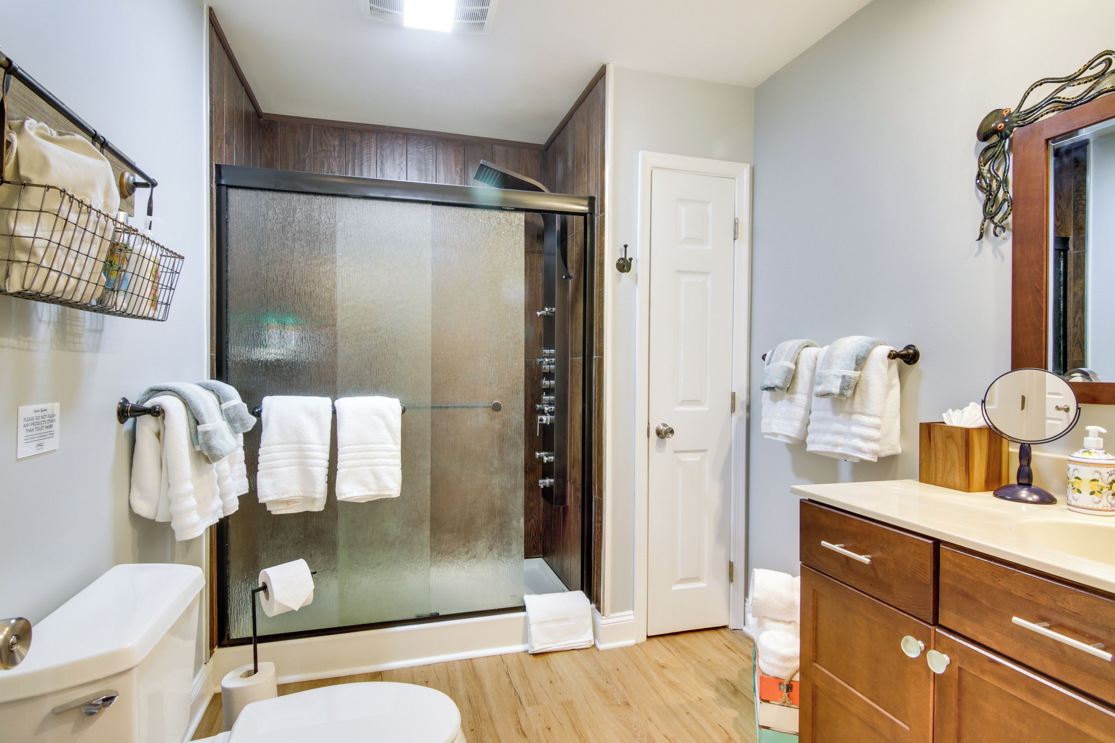Une salle de bain moderne avec une douche à parois de verre, un meuble-lavabo en bois et des toilettes blanches.
