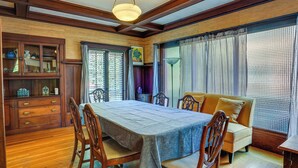 A dining area with a wooden table and chairs, a sofa, and a cabinet with glass doors.