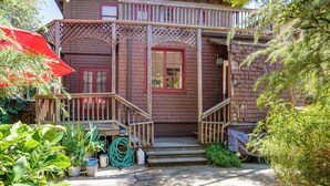 A wooden house with a porch, steps, and potted plants.
