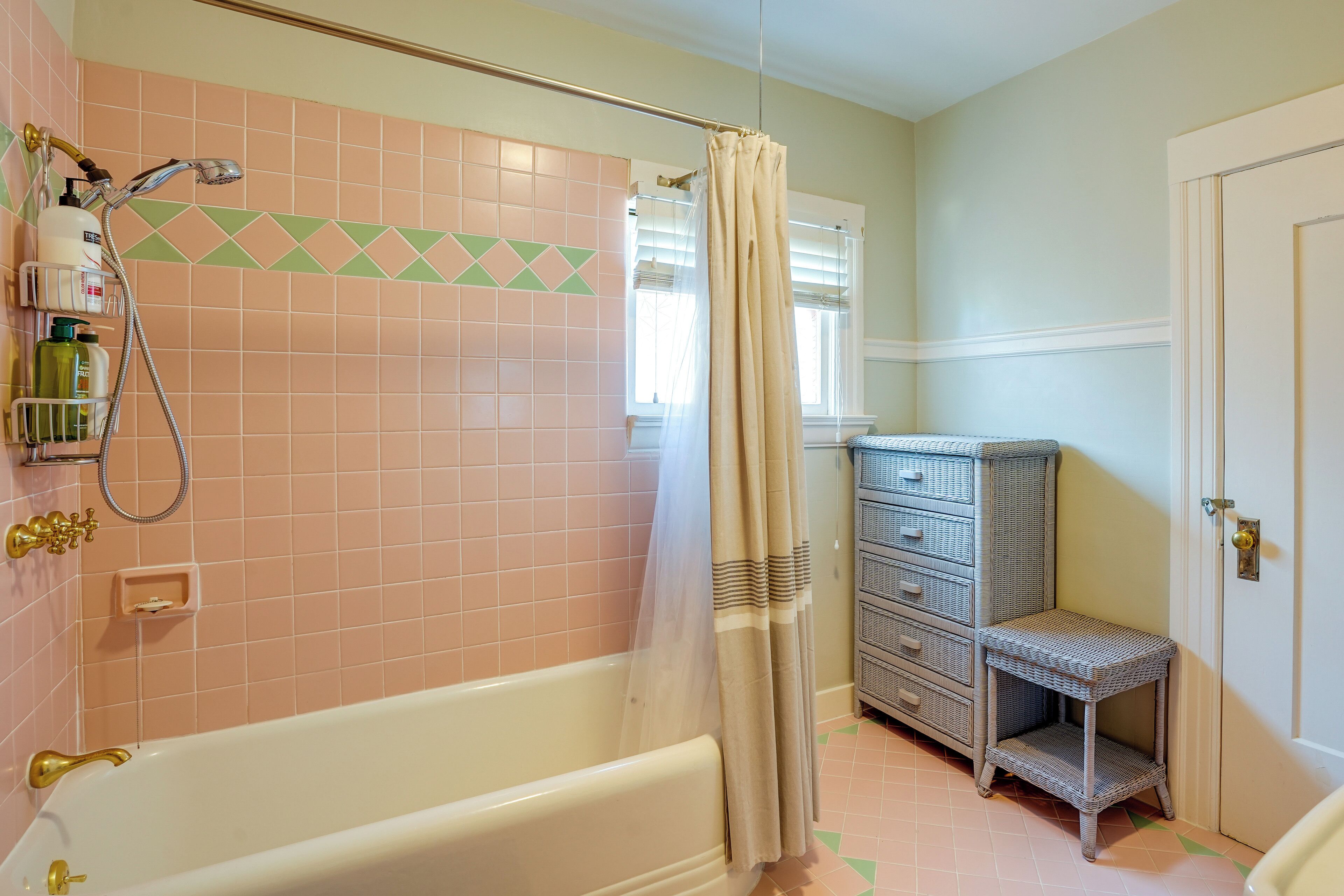 A bathroom with a bathtub, shower, and a wicker shelf.