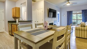 Un vaste espace de vie comprenant une table à manger, des chaises en bois, un canapé et un téléviseur fixé au mur.