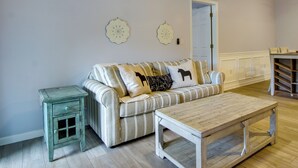Un salon avec un canapé à rayures, une petite table d’appoint en bois et une table basse en bois.