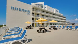 A beachfront hotel with multiple balconies, sun loungers, and outdoor tables. - Ocean-view Jersey Shore Condo: Walk to Beach! (Wildwood Crest)