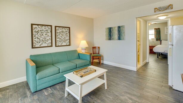 A living room with a teal sofa, a white coffee table, and artwork on the walls. - Ocean-view Jersey Shore Condo: Walk to Beach! (Wildwood Crest)