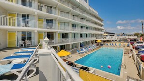 A multi-story hotel with balconies, a swimming pool, and sun loungers. - Ocean-view Jersey Shore Condo: Walk to Beach! (Wildwood Crest)