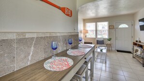 A kitchen with a long countertop, two blue wine glasses, and a decorative orange paddle on the wall.