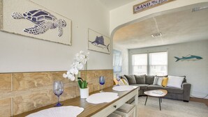 A dining area with a wooden table, white placemats, and a potted orchid. - Wildwood Crest Getaway w/ Deck, Walk to Beach! (Wildwood Crest)