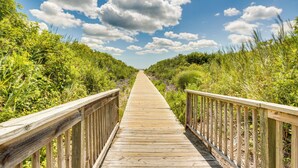 A wooden boardwalk leading through a natural area with dense vegetation on both sides. - Wildwood Crest Getaway w/ Deck, Walk to Beach! (Wildwood Crest)
