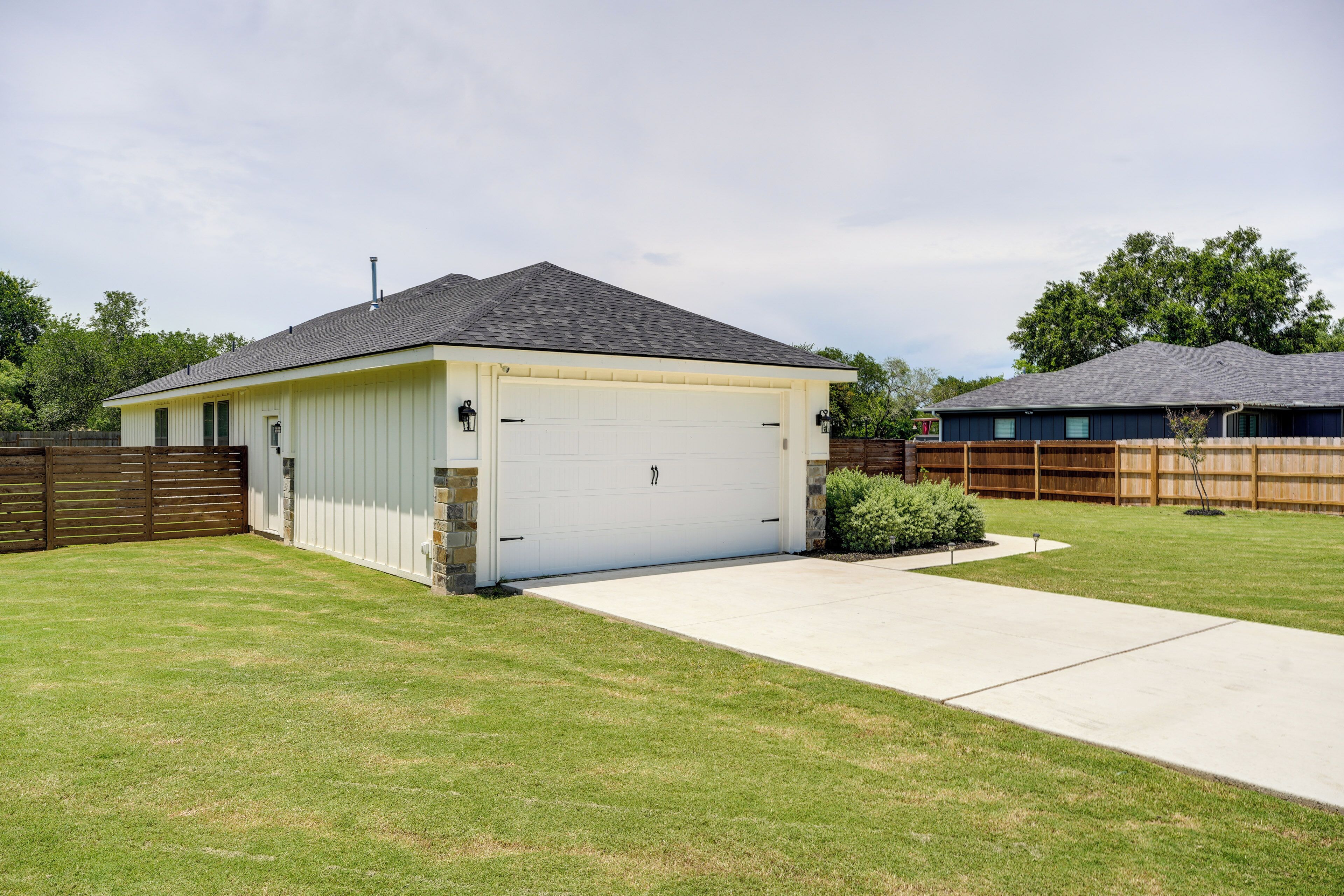 Ein Bungalow mit Garage, Vorgarten und Holzzaun.