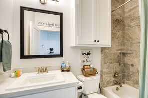 A bathroom with a white sink, a toilet, and a bathtub. There is a sign on the wall that says 'wash soak relax'.