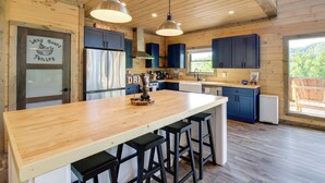 Une cuisine moderne avec un îlot central en bois, des tabourets de bar et des luminaires suspendus.