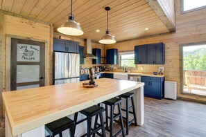 Une cuisine moderne avec un îlot central en bois, des tabourets de bar et des luminaires suspendus.