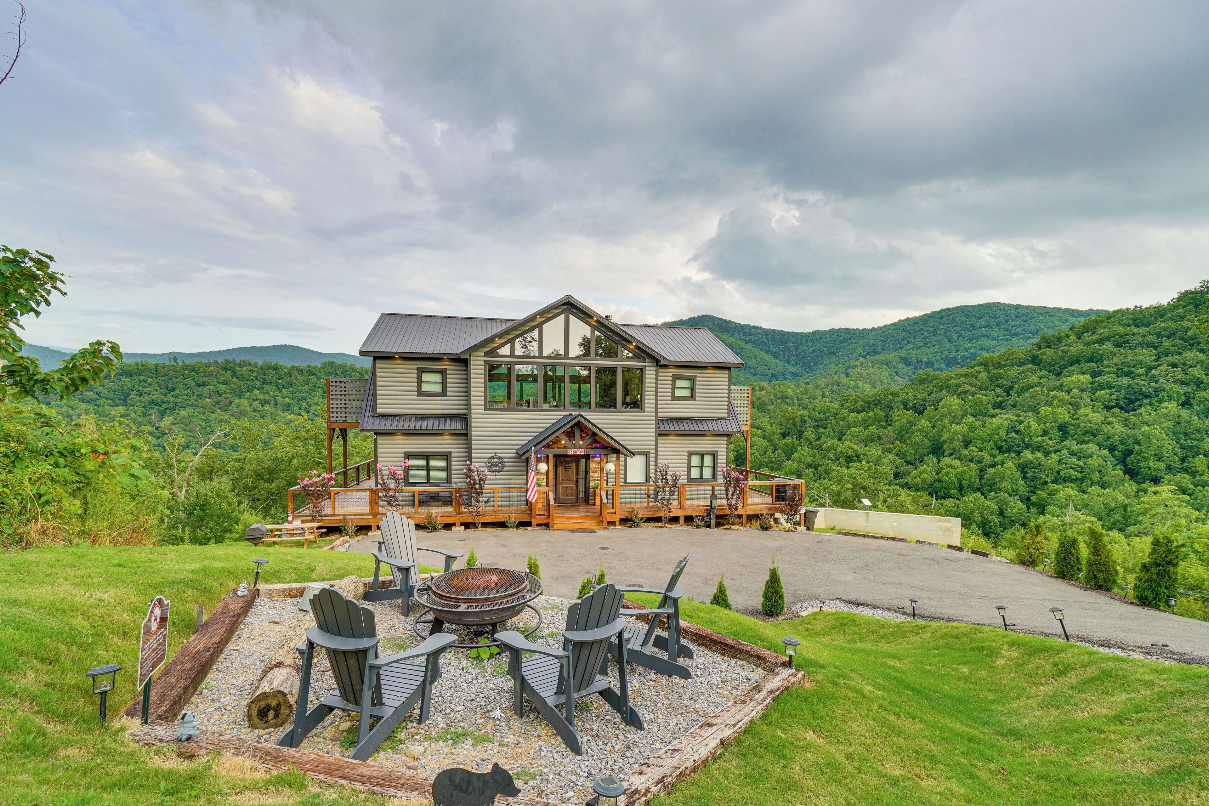 A large house with a deck, outdoor seating, and a fire pit.
