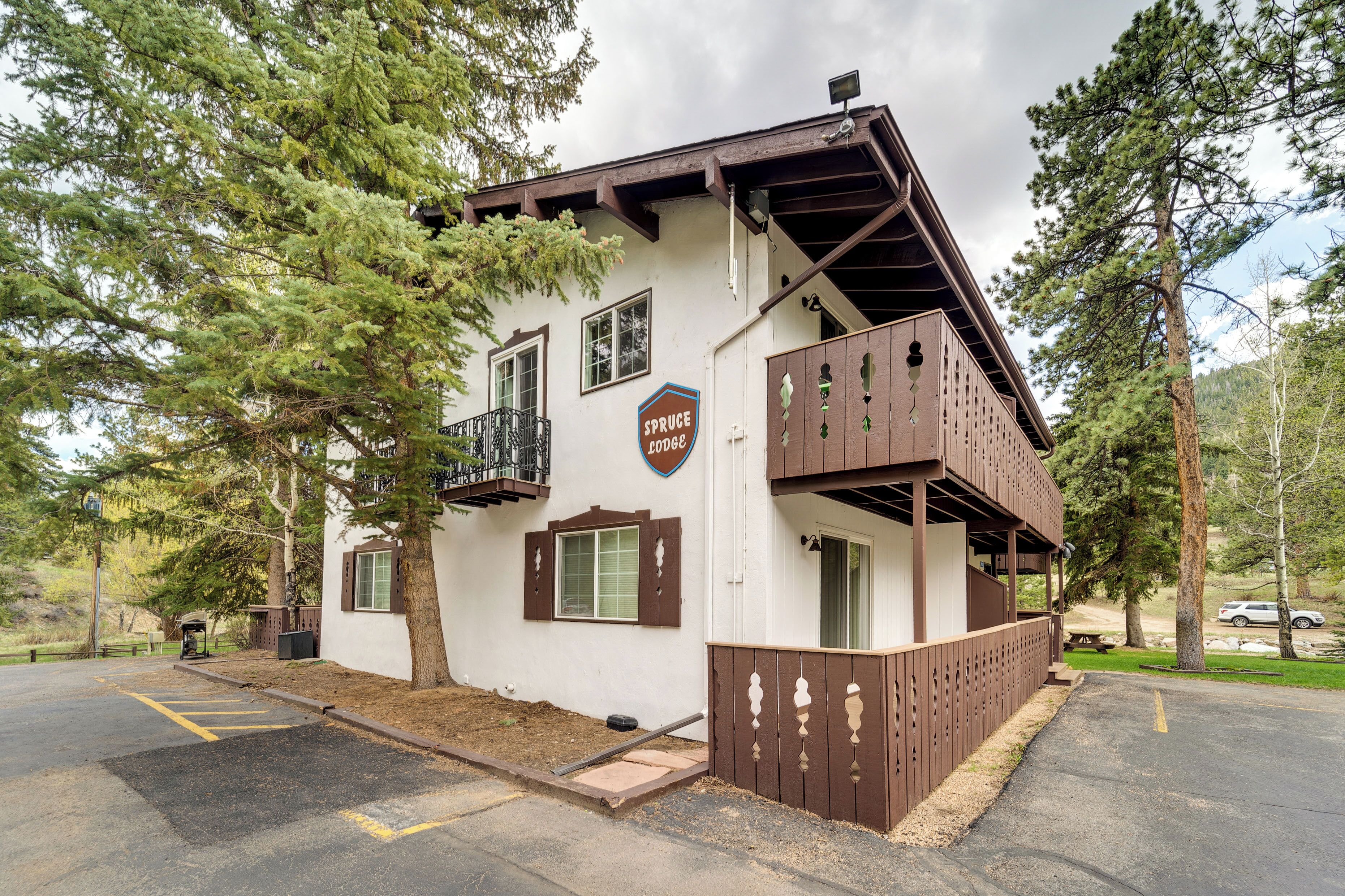 Un chalet à l’extérieur blanc, doté d’un balcon et d’une enseigne indiquant « Spruce Lodge ».
