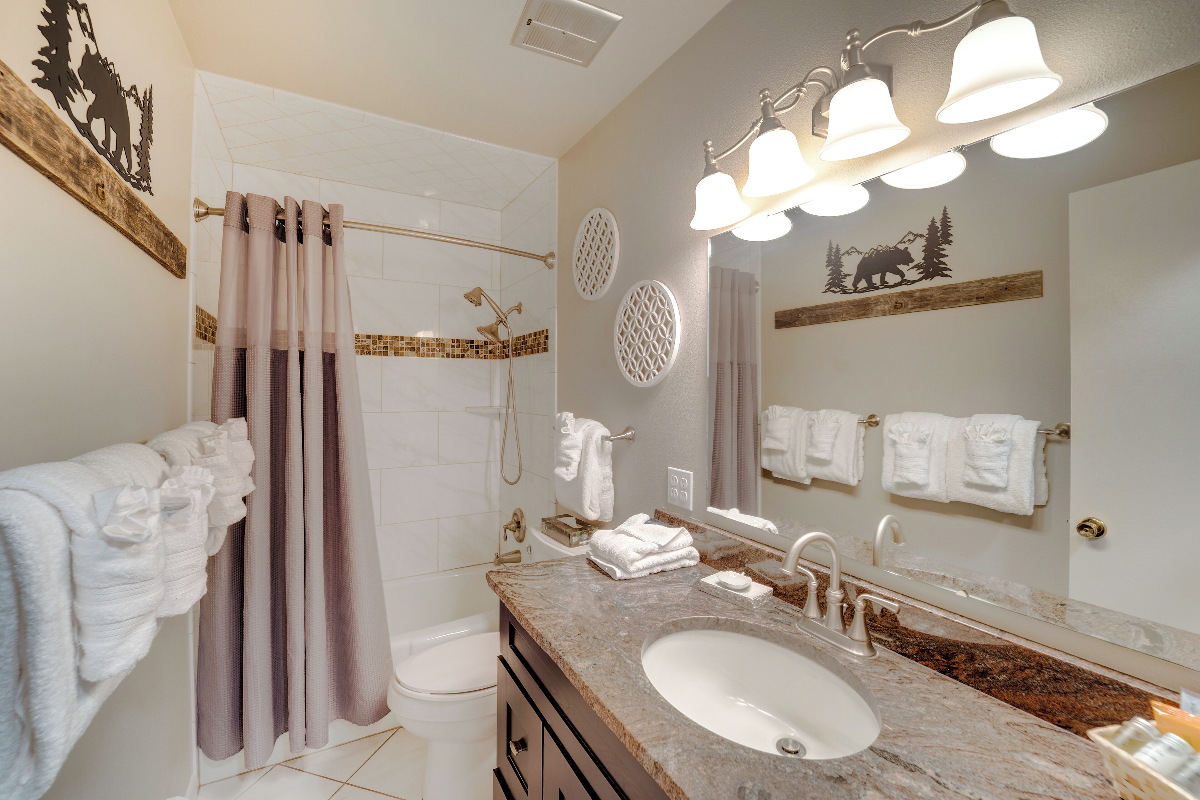 A bathroom with a sink, mirror, shower, and towel racks.