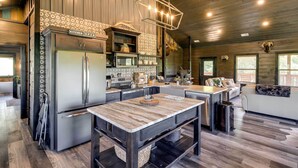 A modern kitchen with stainless steel appliances, a wooden island, and a hanging light fixture.
