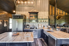 A modern kitchen with a marble countertop, stainless steel appliances, and a deer head mounted on the wall. - Upscale Sevierville Cabin w/ Hot Tub & Views! (Sevierville)