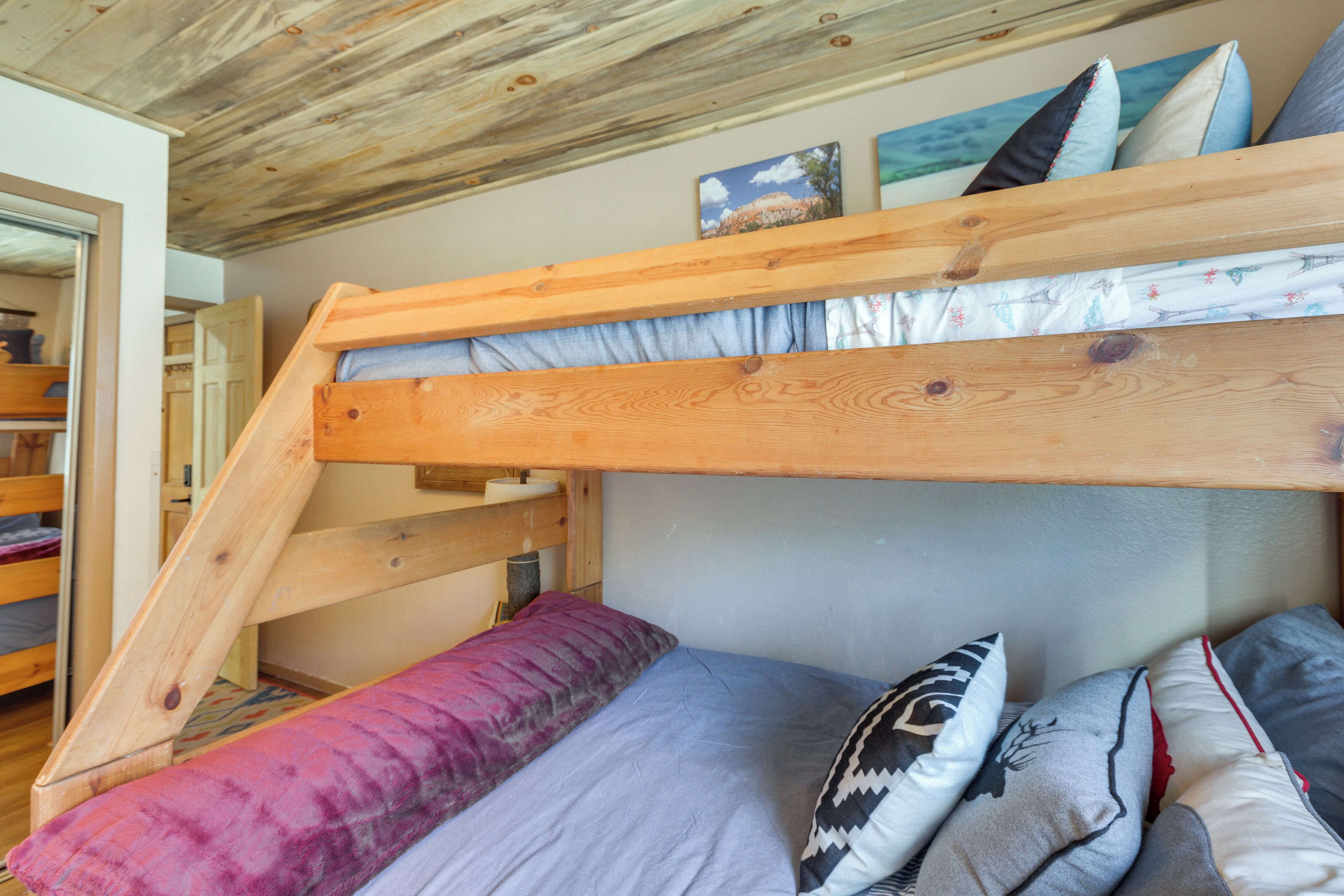 A bunk bed with a wooden frame, a mattress, and several pillows.