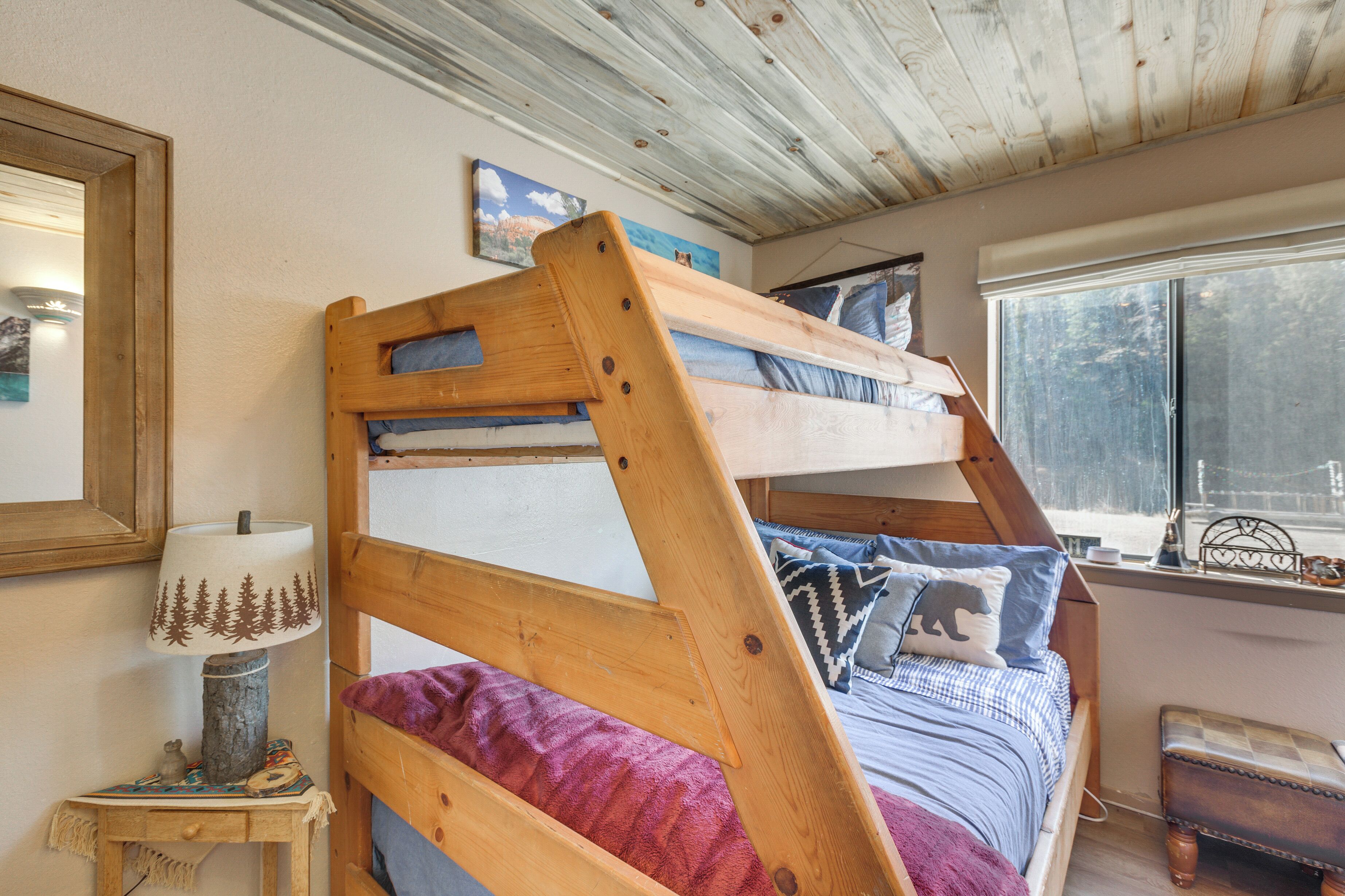 A bunk bed with a wooden headboard, a bedside table with a lamp, and a window with a view of the outside.