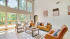 A spacious living room with a large window, a wooden coffee table, a sofa, and a leather armchair.