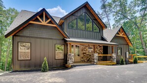A two-story lodge with a stone facade, large windows, and a covered porch.