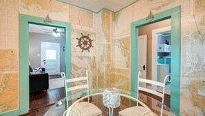 A room with a glass table, white chairs, a map wall, and a door leading to another room. - New Braunfels Vacation Rental on Lake Dunlap! (New Braunfels)