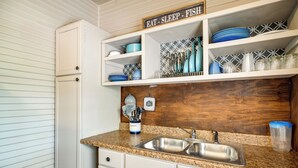 A kitchen with white cabinets, a granite countertop, a double sink, and a backsplash with a geometric pattern. - New Braunfels Vacation Rental on Lake Dunlap! (New Braunfels)