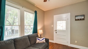 A living room with a grey sofa, teal curtains, a lamp, and a door labeled "Lake House". - New Braunfels Vacation Rental on Lake Dunlap! (New Braunfels)
