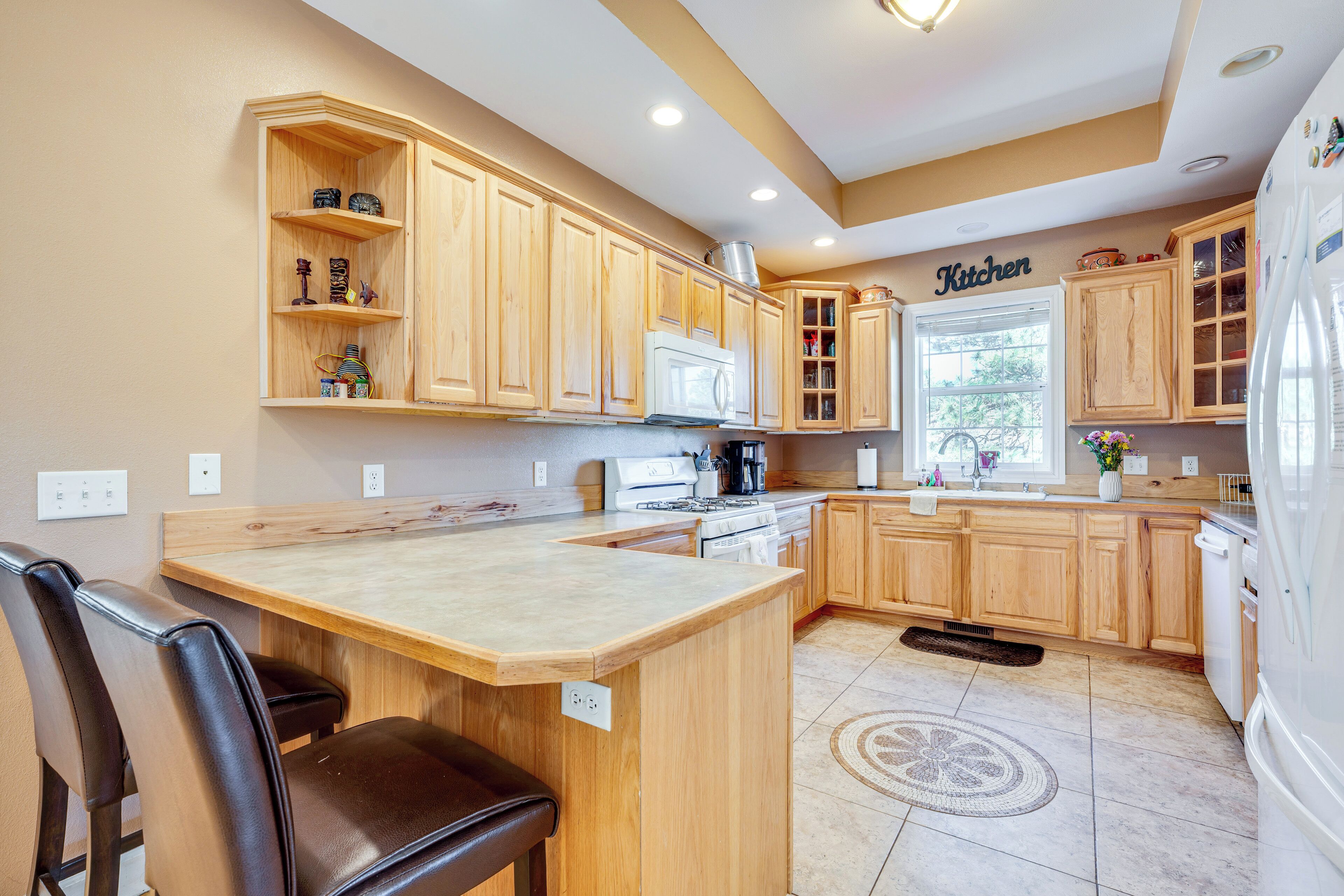A kitchen with wooden cabinets, a central island, a refrigerator, and a window.