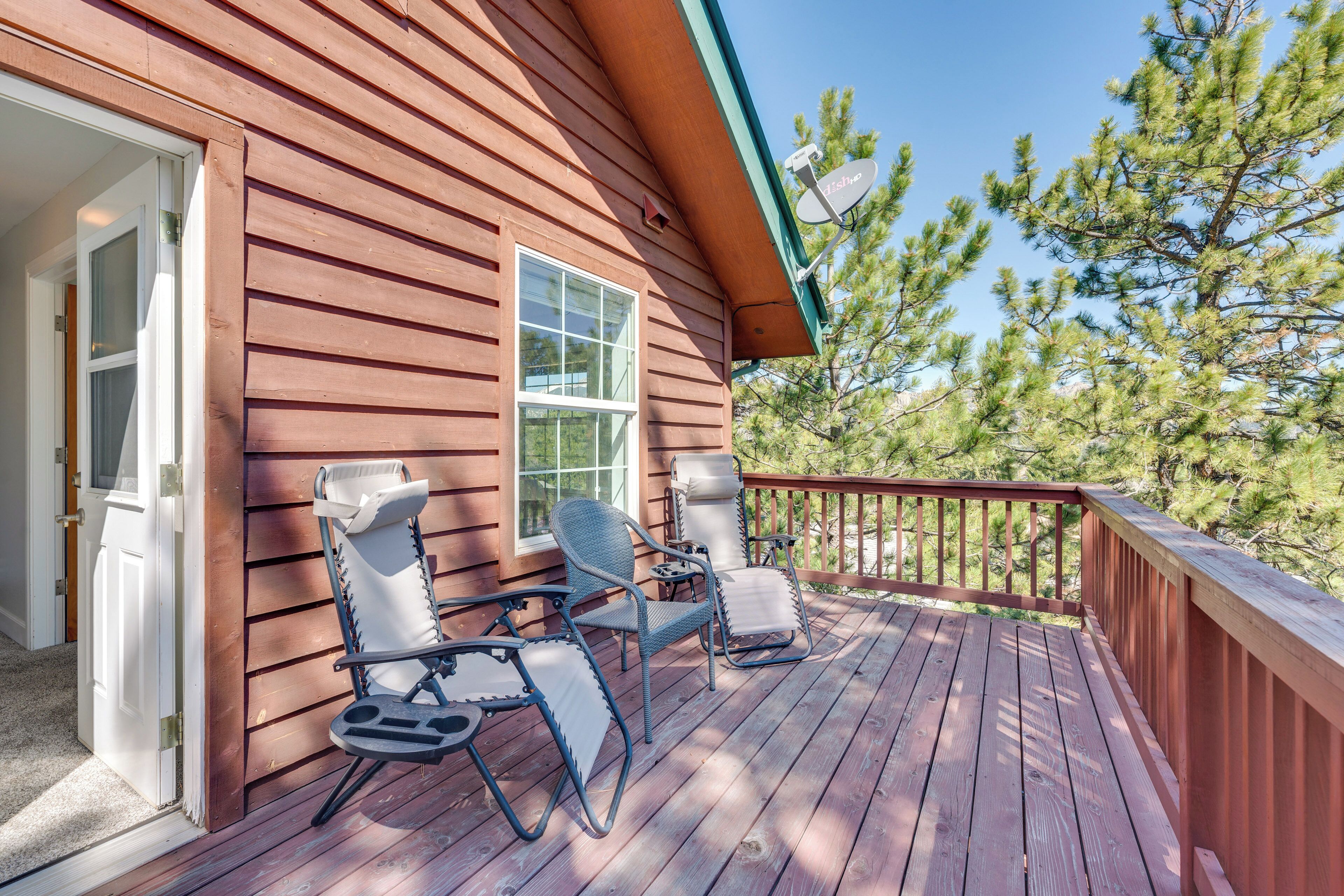 A wooden deck with two chairs and a table, a door, and a satellite dish.